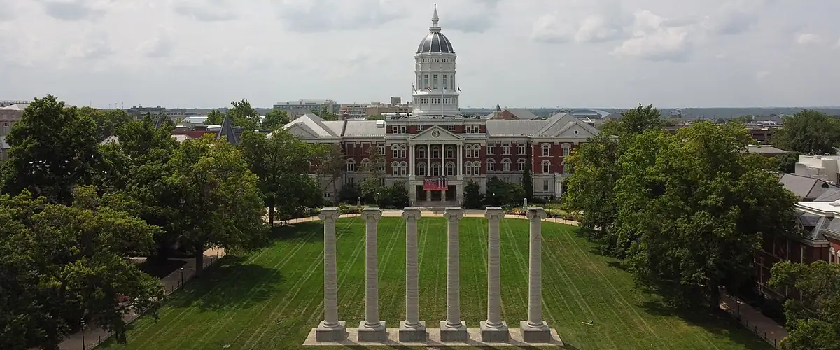 Aerial view down the Francis Quadrangle: six stone columns on the lawn in front of Jesse Hall&rsquo;s white dome